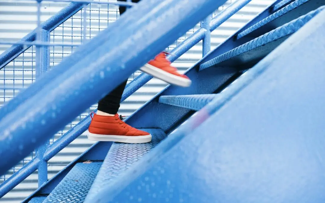 Red shoes climbing blue metal stairs